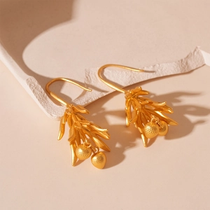 Vintage matte gold floral drop earrings with leaf design on a textured stone surface
