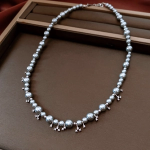 Detail of grey-blue pearl necklace featuring a zircon encrusted silver pendant on a tray