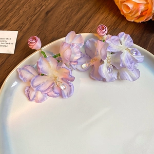 Detail of purple fabric flower earrings with tassel bead on white ceramic tray