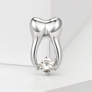 Macro shot of silver tooth brooch featuring a large round clear crystal on white background