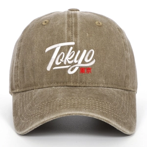 Detail of white Tokyo embroidery and red Japanese text on washed khaki baseball cap