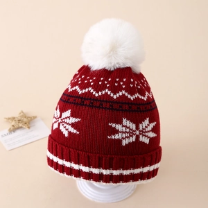 Close-up of red knit Christmas beanie with white snowflake patterns and soft pom-pom