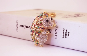 Detail of crystal hedgehog keychain with colorful rhinestones on a vintage book