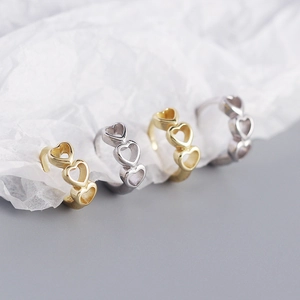 Macro view of four s925 silver heart shaped ear cuffs in gold and silver polished finishes