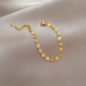 Close-up of golden titanium steel smiley face link bracelet on silk fabric