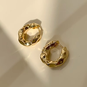 Detailed view of golden hoop earrings featuring a unique hammered irregular texture finish