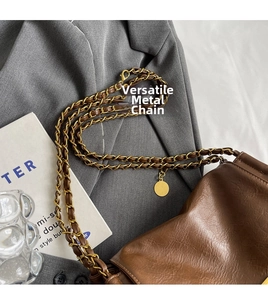 Detail of dark brown pebble leather shoulder bag with gold chain and strap texture