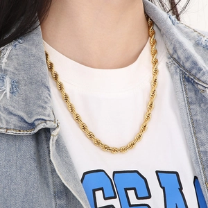 Golden stainless steel twist chain necklace worn by a model on a blue denim jacket