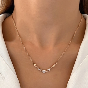 Close-up of a delicate rose gold heart necklace with micro-set zircon on model