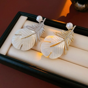Macro detail of tropical leaf earrings with iridescent pearl and cubic zirconia stones