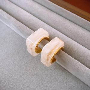 Gros plan sur des boucles d'oreilles en résine marbrée en forme de C avec intérieur doré