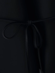 Détail de la ceinture noire avec nœud papillon sur une robe ajustée à manches longues