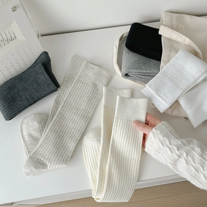 Knee-high ribbed cotton socks in neutral tones showing elastic knit texture and softness