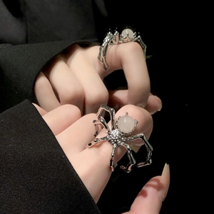Detailed view of punk spider ring with moonstone worn by a model on black fabric