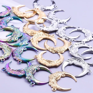 Detailed view of crescent moon pendants with floral embossing in gold, silver, and rainbow