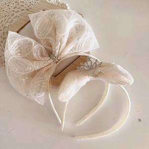 Détail de deux serre-têtes crème pour enfants avec nœuds en tulle à paillettes et couronne