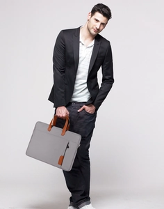 Slanke 14-inch laptophoes in grijs met bruine handvatten vastgehouden door een model op kantoor