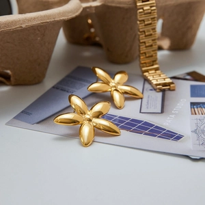 Macro detail of high-shine gold flower earrings on artistic studio display card