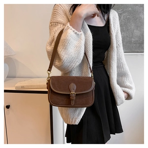 Detail of vintage brown shoulder bag showing suede stitching and retro gold buckle