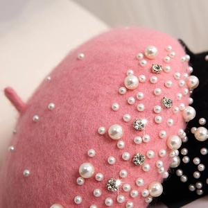 Detailed close-up of pink wool beret featuring white pearls and sparkling rhinestones