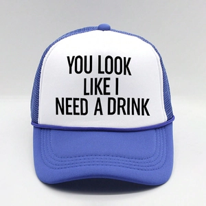 Detail of the blue trucker hat featuring YOU LOOK LIKE I NEED A DRINK printed on foam