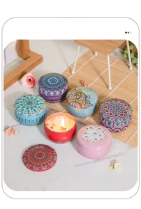 Close-up of scented candles in mandala tins with dried petals on a marble surface
