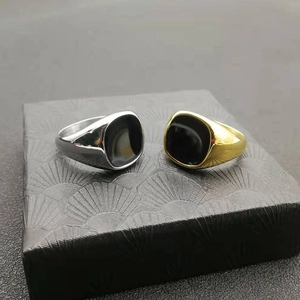 Gold and silver signet rings with black rectangular inlay on a textured jewelry box