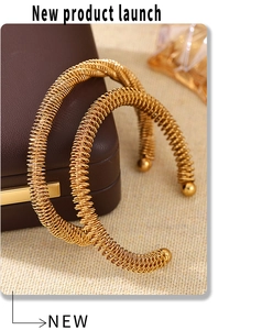 Close-up of golden spring coil bracelet with metal ball ends on a leather jewelry box