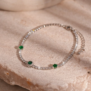 Detailed close-up of emerald green zircon tennis bracelet on natural stone base