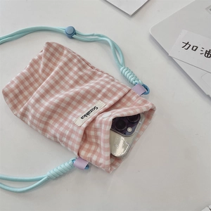 Detail view of plaid canvas phone pouch with blue adjustable rope and brand tag