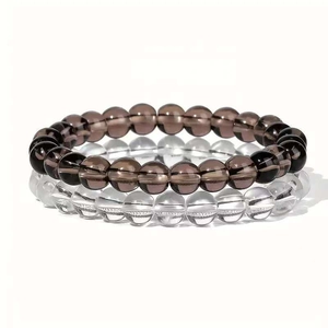 Set aus 8mm Rauchquarz- und klaren Kristallperlenarmbändern auf weißem Hintergrund