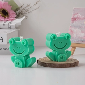 Cute green frog-shaped scented candles on a wooden base for creative home decor and gifts