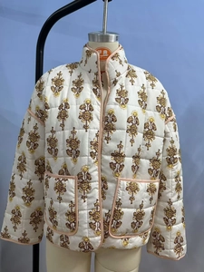 Close-up of white quilted jacket with vintage floral patterns and pink trim detailing