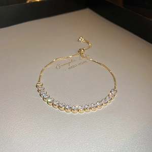 Close-up of golden wavy diamond bracelet featuring a sliding clasp and zircon inlay