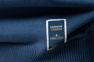 Macro detail of blue knitted cotton sweater neckline showing fine texture and woven label
