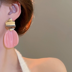 Detail of pink resin oval earrings with gold irregular top on model's ear