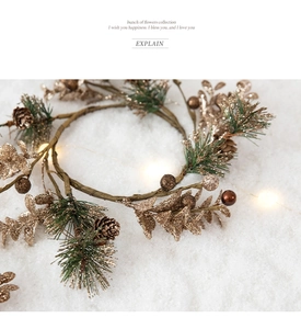 Close-up of golden Christmas wreath branch with pine cones and warm LED string lights