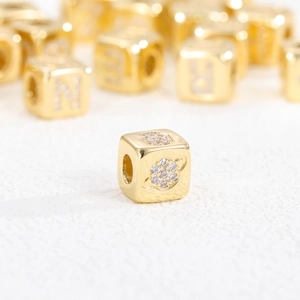 Macro shot of 18K gold plated dice bead featuring zircon inlays and a Saturn motif