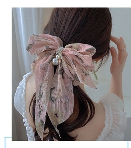 Barrette à nœud en mousseline fleurie rose avec perle montrée sur l'arrière de la tête