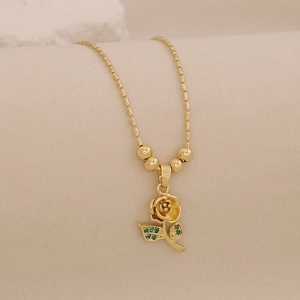Detail of 18K gold rose pendant necklace with green gemstone leaf and bead chain
