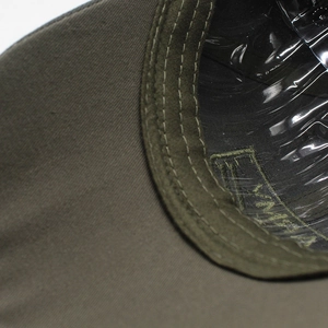 Detail of army green baseball cap showing peak stitching and interior sweatband