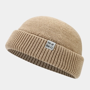 Detailed close-up of khaki knitted docker hat featuring a textile label and rolled edge