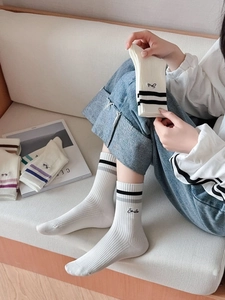 Detail of white cotton athletic socks with stripes and Smile embroidery in a cozy setting