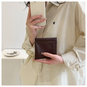 Detail view of a mini dark brown leather square coin purse with metal clasp closure