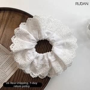 Detailed close-up of white lace pleated hair scrunchie with layered wavy hollow embroidery
