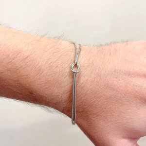 Silver stainless steel snake chain bracelet with a central knot design on wrist