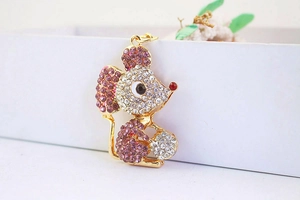 Detailed macro view of golden mouse keychain with clear and purple rhinestones
