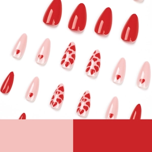 Pink heart press-on nails set with long pointed tips and solid red colors on white backdrop