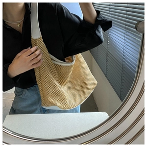 Close-up of woven straw shoulder bag with white leather trim in a mirror selfie