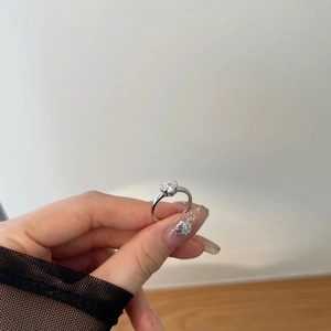 Close-up of hand holding silver ring with sparkling heart-shaped clear cubic zirconia stone